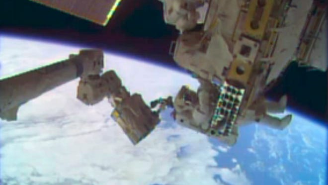 In this image taken from video provided by NASA, astronauts Rick Mastracchio, top, and Michael Hopkins work to repair an external cooling line on the International Space Station on Tuesday, Dec. 24, 2013, 260 miles above Earth. The external cooling line — one of two — shut down Dec. 11. The six-man crew had to turn off all nonessential equipment, including experiments. (AP Photo/NASA)