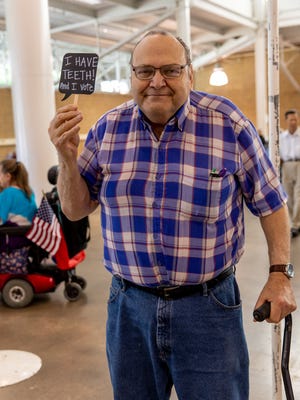 Senior citizen Robert Campbell holds a sign after mailing in a toothbrush at a senior health fair earlier this year.