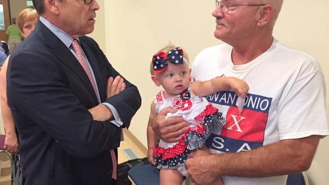Rick Perry talks Saturday in Rockwell City with Kent Gray of Pomeroy, who was holding Mila Morgensen, his 13-month-old granddaughter.