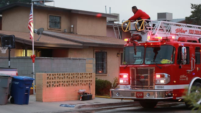 A firefighter directs a light toward the apartment where a fire erupted Wednesday afternoon in the 10600 block of Cuatro Vistas Drive in East El Paso.