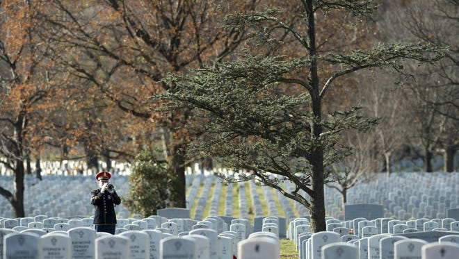 A bugler from the U.S. Army Band, "Pershing's Own," plays taps during a burial service at Arlington National Cemetery.