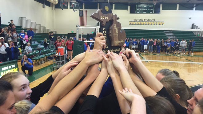 Harper Creek players raise their Class B district championship trophy at Pennfield High School on Thursday.