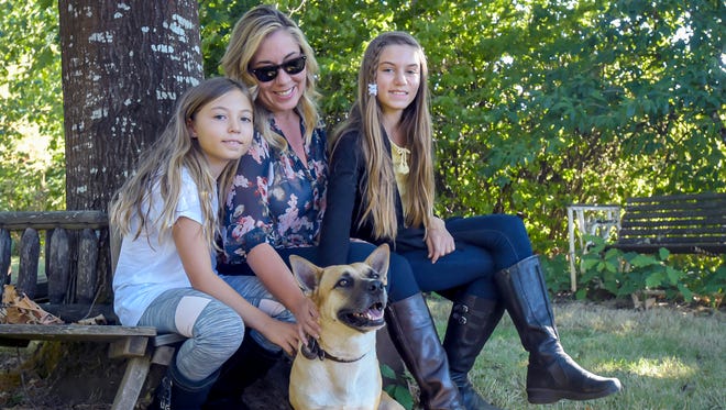 In an Oct. 6, 2017 photo, Bakker family members from left Izzy, 9, Holly and Ally, 11, have been reuinted with Gustavo, "Gus" for short, a 4-year-old Corgi-German Shepherd mix, who is now in Philomath Ore., after surviving hurricane Maria in Puerto Rico. The corgi-German shepherd mix is a native of Puerto Rico and rode out Hurricane Maria late last month inside a boarding kennel on the island. Ten days after the storm hit, devastating the Caribbean island, the pup was reunited with his family in the United States.