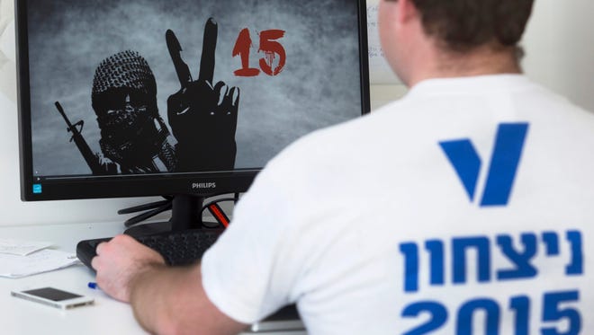 A volunteer worker at V15 looks at a commercial  by the Likud Party showing a masked Hamas fighter making the V sign (for Victory) next to the number 15 in a direct reference to the V15 organization in Tel Aviv on Feb. 4. The V15 organization  backs a change in government for the general elections March 17.