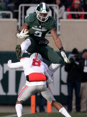 Sophomore running back LJ Scott leaps over Ohio State cornerback Gareon Conley during the game against Ohio State on Saturday, Nov. 19, 2016 at Spartan Stadium in East Lansing.