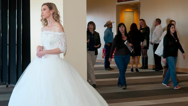 Sarah Kidd, modeling a bridal dress from Renee's Bridal, meets bridal show goers at the entrance of the Las Cruces Convention Center at the 2016 showcase.