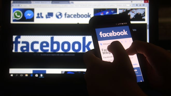 A cellphone and a computer screen display the logo of the social networking site Facebook on March 22, 2018.