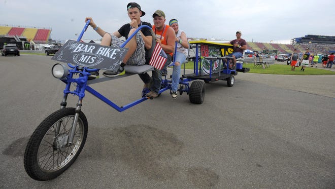 Austin Smith, front, Dawson Gregory and Seth Johnson all of Belding, pedal to pull Bob Huddleston on their bar bicycle.