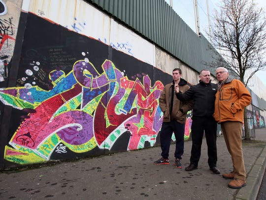 A Tour guide shows tourists a peace wall in north Belfast on Jan. 23, 2017.
