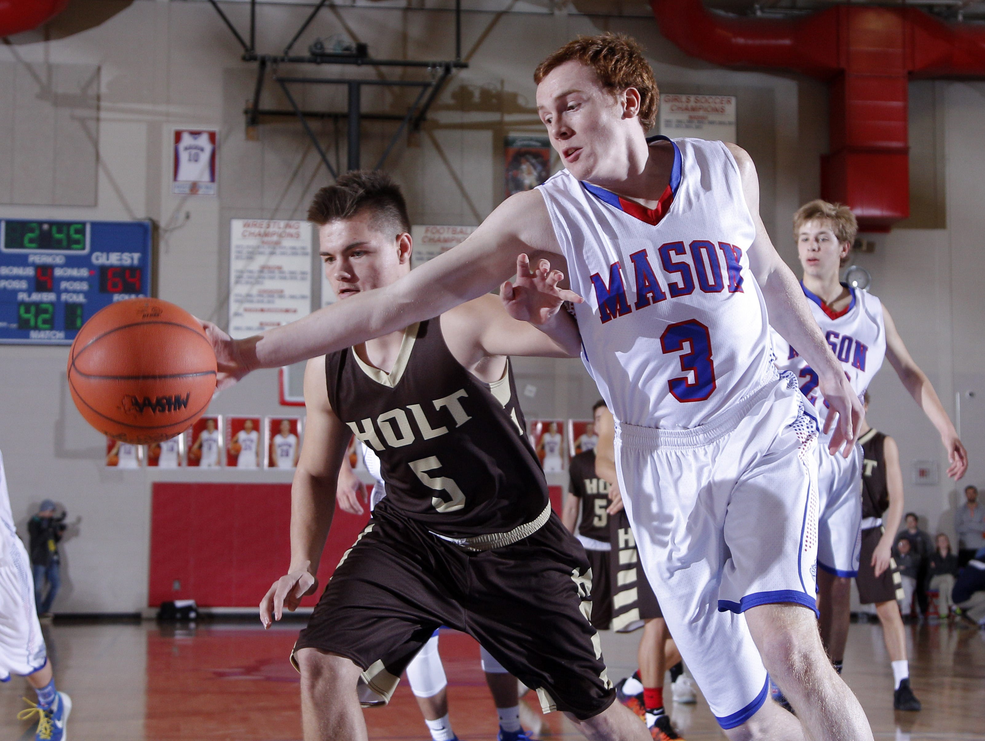 Mason's Brooks Mires (3) and Holt's Owen Brown (5) chase down the ball during their district final Friday, March 10, 2017, in Mason, Mich. Holt won 74-44.