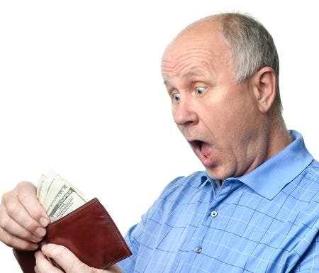 A surprised senior man looking at cash in his wallet.