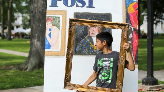 Andrew Basler, 11, of Appleton recreates "Framed" the Norman Rockwell painting that appeared on a Saturday Evening Post cover in 1946. Basler was in a Rockwell Photo Booth area as the Trout Museum of Art held the 55th Annual Art at the Park at City Park in Appleton, Wis., Sunday, July 26, 2015. Visitors could mimic famous Rockwell paintings and have their photo taken during the event. The museum is holding a Rockwell exhibition through October 25.Ron Page/Post-Crescent Media