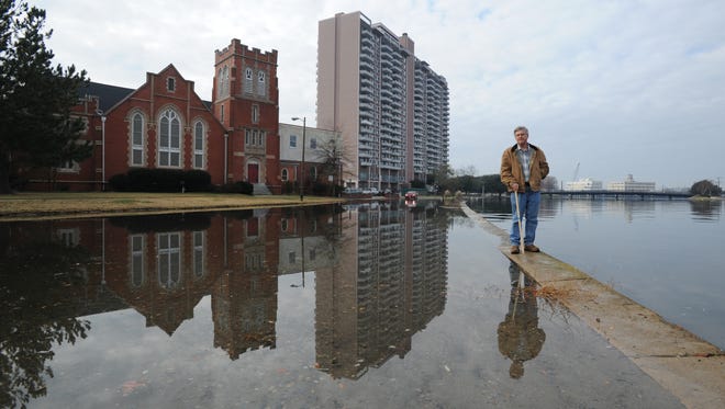 Skip Stiles, executive director of Wetlands Watch, stands on a flood wall in a neighborhood of Norfolk that is regularly flooded by high tides because of a rising sea level.