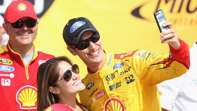 Joey Logano and his wife Brittany celebrate in victory lane after winning the NASCAR Sprint Cup Series FireKeepers Casino 400 at Michigan International Speedway Sunday in Brooklyn, Michigan.
