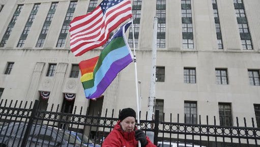 Cindy Clardy, 63, of Southfield  waves her rainbow flag  and American Flag across the street from the Theodore Levin Federal Court in Detroit as the trial to overturn the ban on gay marriage continued Tuesday Mar. 4, 2014.