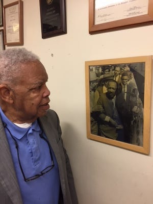 Fred Davis looks at a photograph of himself standing just behind Dr. Martin Luther King Jr. as they prepare to march for striking sanitation workers March 28, 1968, in Memphis.