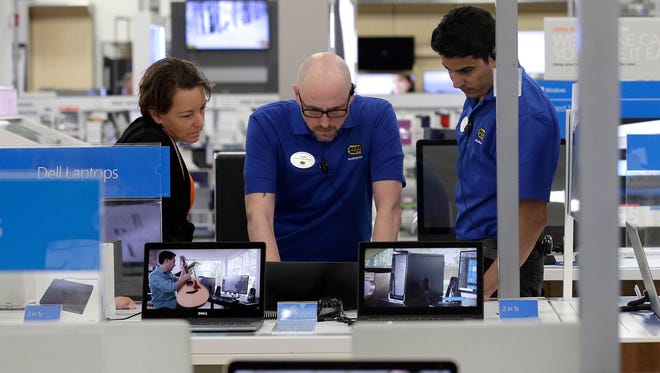 Employees assist a customer, at left, with a computer at Best Buy in Cary, N.C. On Friday, June 30, 2017, the Commerce Department issues its May report on consumer spending.