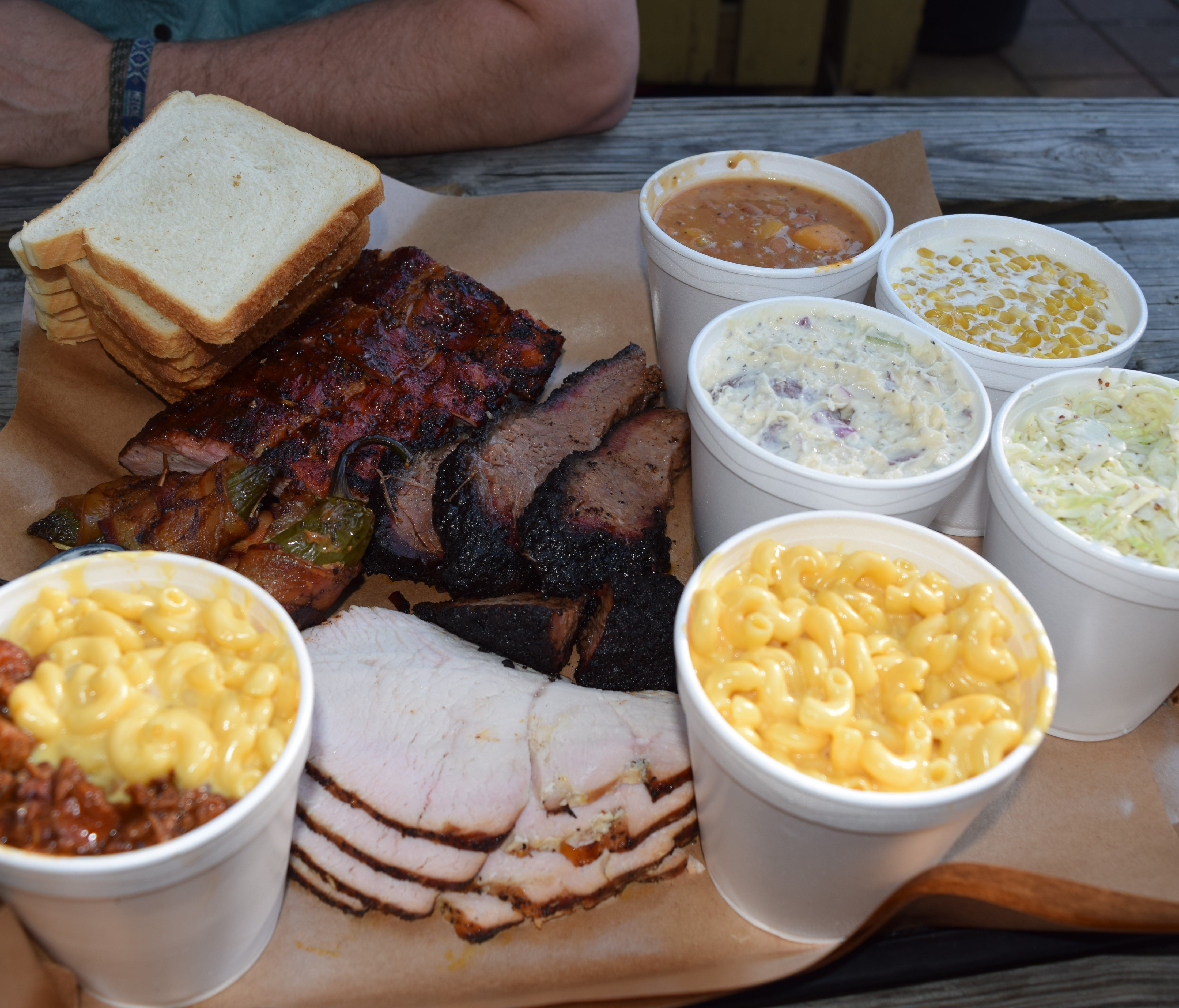 A mixed platter features all the specialties: cherry glazed baby back ribs, beef brisket, bacon-wrapped jalapenos, turkey, and a slate of side dishes including the meat and cheese Cheesy Chop.