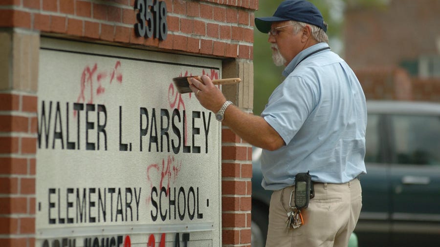 Tom Dixon with the New Hanover County Schools Maintenance Department uses lacquer thinner and a paint brush to remove spray paint graffiti from the marquee outside Walter L. Parsley Elementary School Wednesday Aug. 23, 2006.