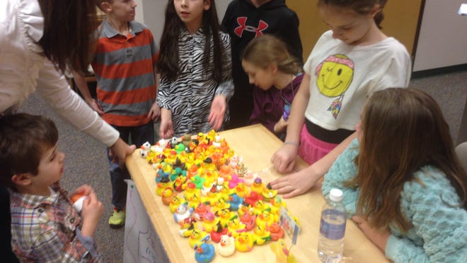 Hope Middle School teacher Katie Bielecki (left) and her son Benjamin, 5, go over a rubber duck sale to help Flint residents before Monday's Holt Board of Education meeting. Shown selling the ducks are (from third from left) are Sawyer Hosford, Julia Toomey, Rodney Stewart, Nadia Weise, Paige Lemmon and Cortney Morgan. Lily Stroud also is a team member.