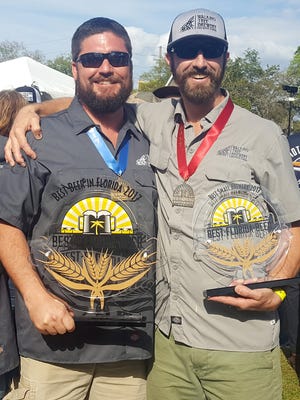 Walking Tree Brewery co-owners Mike Malone and Alan Dritenbas wear medals and hold trophies from the Best Florida Beer Professional Championship in Tampa.