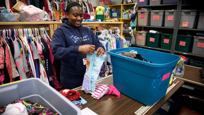 File photo: Saint’s Place Clothing Closet volunteer Aubine Zinsou folds clothes at the store. Zinsou, a refugee from Togo in West Africa, received clothing from the store when she and her family first came to Rochester.