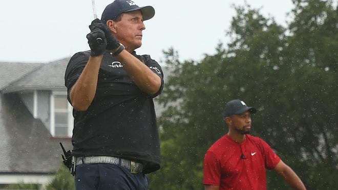 Phil Mickelson plays his shot from the first tee as Tiger Woods looks on during The Match: Champions for Charity Sunday at the Medalist Golf Club in Hobe Sound.
