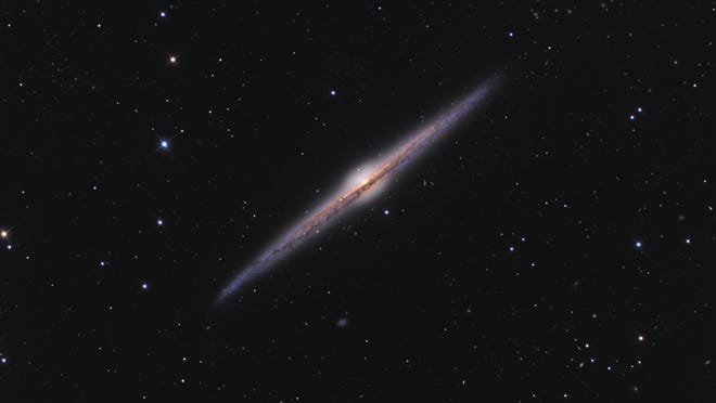 Spiral galaxy NGC 4565, in the constellation Coma Berenices, is oriented edge-on as seen from Earth. A 10-inch telescope will easily show the dusty lane through the spiral arms. A similar dusty lane can be seen in the Milky Way Band, through the Cygnus and Aquilia constellations. [Photo by Ken Crawford (Own work) [CC BY-SA 3 (https://creativecommons.org/licenses/by-sa/3)], via Wikimedia Commons]