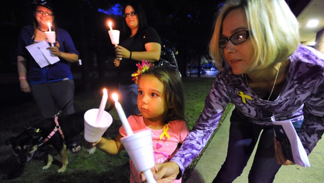 Kyndle Clark lights daughter Kynee’s candle during Tuesday’s Vigil for Suicide Awareness on the campus of Ohio University-Chillicothe.