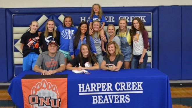 Harper Creek's Katie Wade (center) is surrounded by family and teammates as she signs to play volleyball at Ohio Northern University.