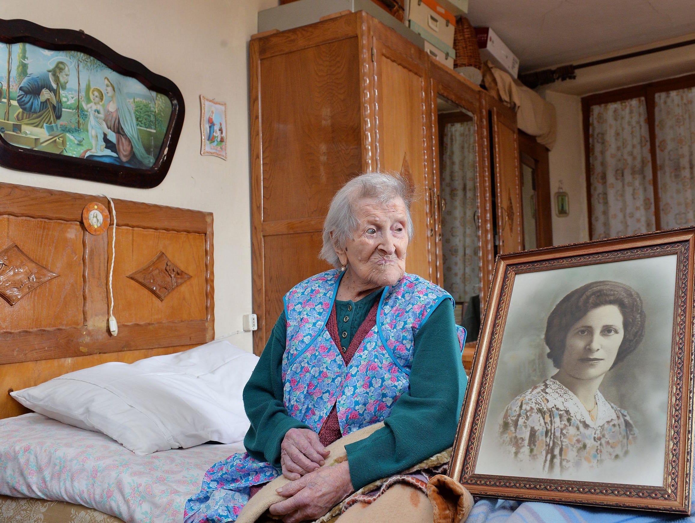 Emma Morano, then 116, sits in her apartment next to a picture depicting her when she was young in Verbania, Northern Italy.