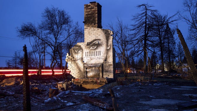 In this Feb. 8, 2019, photo, a mural by artist Shane Grammer adorns the chimney of a residence leveled by the Camp Fire in Paradise, Calif. Grammer says he painted murals throughout the fire-ravaged town to convey hope in the midst of destruction.