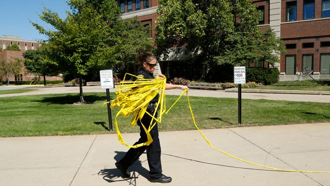Police tape is collected after the all clear is given following a bomb threat shortly after 11 a.m. Wednesday, September 23, 2015, at Schleman Hall. According to police, an employee inside Schleman received a telephone call from a woman with an international accent stating there was a bomb in the building. After an extensive search, police gave the all clear and employees returned to Schleman Hall.
