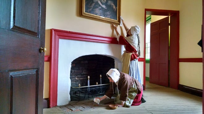 Historical-site interpreters at the John Dickinson Plantation demonstrate cleaning methods. Jennifer Dunham wipes a painting while Melissa Fitzgerald cleans the hearth.