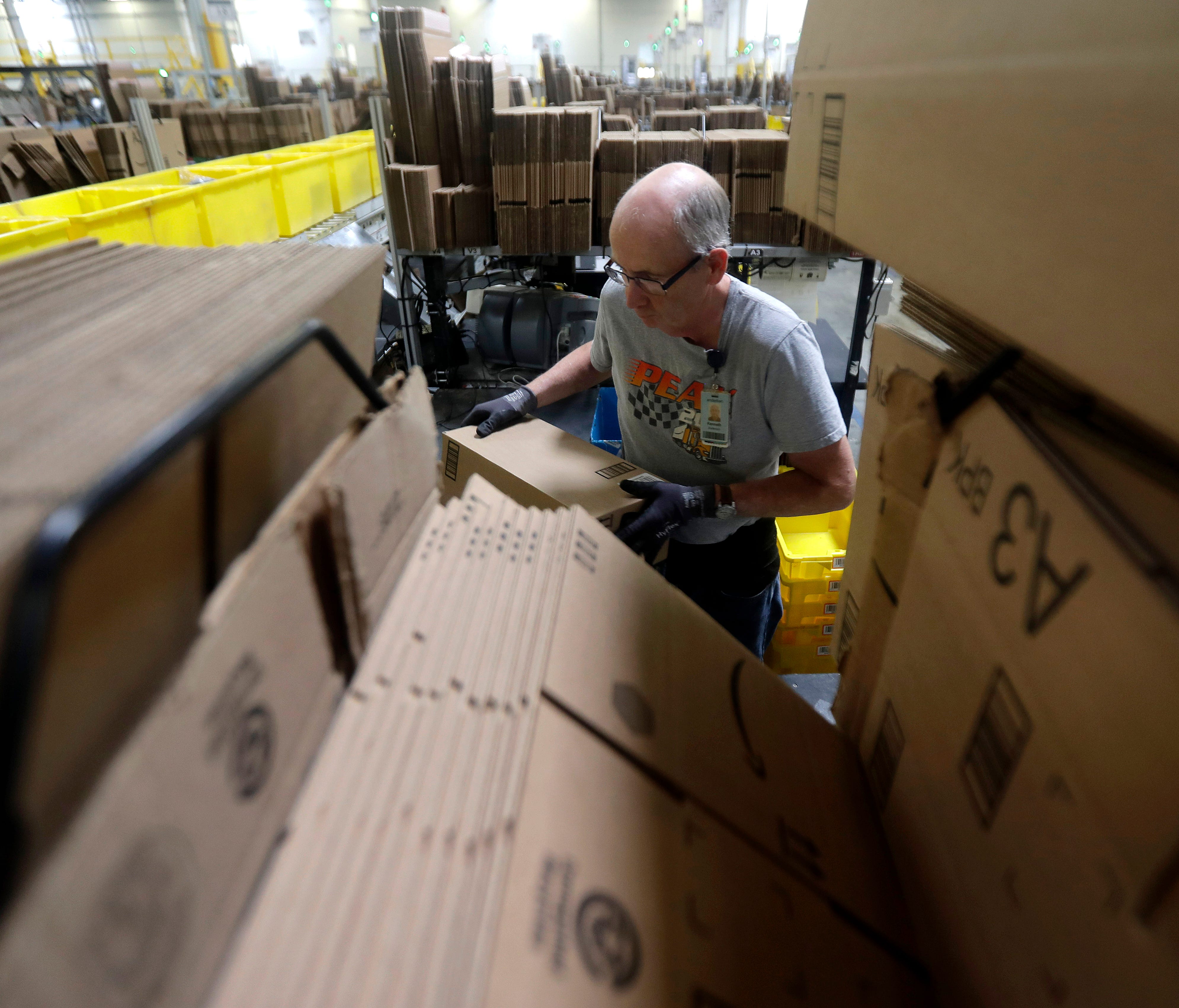 In this Tuesday, Aug. 1, 2017, photo, Amazon employee Kenneth Anderson loads boxes at the Amazon Fulfillment center in Robbinsville Township, N.J. Amazon is holding a giant job fair Wednesday, Aug. 2, and plans to make thousands of job offers on the 