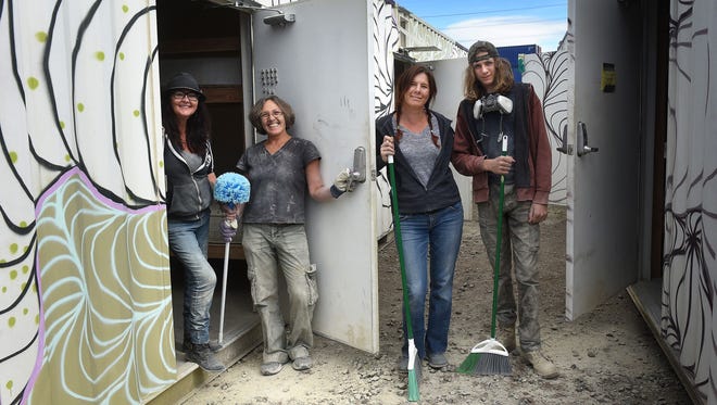 Linda Zaharoff, left; Erika Wesnousky; Jen Martini; and Sebastian Martini help clean up some shipping containers Oct. 21, 2017, that have been outfitted as sleeping quarters for the Burning Man festival. The containers being stored in Sparks, Nev., are being shipped to Northern California as temporary shelters for a school of special-needs children who lost their homes in the wildfires.