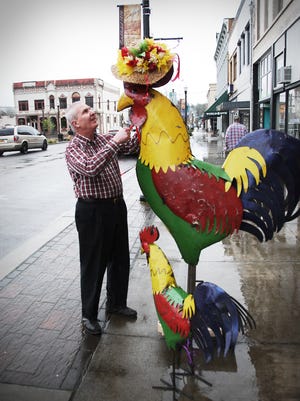 Mike Berkes, owner of Some Things, adjusts the latest head covering — an Easter bonnet — for his painted metal chicken decoration outside his business on Main Street in downtown Dallas. In front is Berkes’ latest acquisition for the site, a smaller, nearly-identical metal chicken.