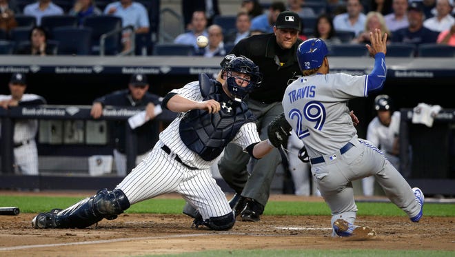 The ball pops out of New York Yankees catcher Brian McCann's glove as he attempts to put the tag on Toronto Blue Jays' Devon Travis (29) during the fourth inning of a baseball game, Wednesday, May 25, 2016, in New York. Travis was safe on the play. Kevin Pillar also scored.