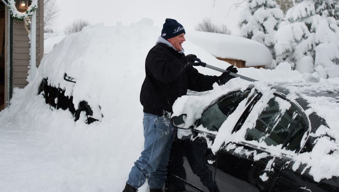 Jeff Strum removes snow off of his car after two days of record-breaking snowfall in Erie, Pennsylvania.