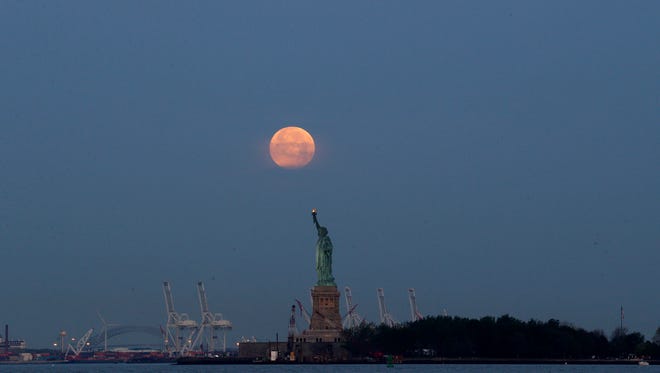 FILE - This Sunday, June 23, 2013 file photo shows a supermoon over the Statue of Liberty in New York. Monday, Nov. 14, 2016 will have the closest full moon of the year, or every 14 months to be precise. It will also be the closest the moon comes to us in almost 69 years. And it won't happen again for another 18 years. (AP Photo/Julio Cortez)