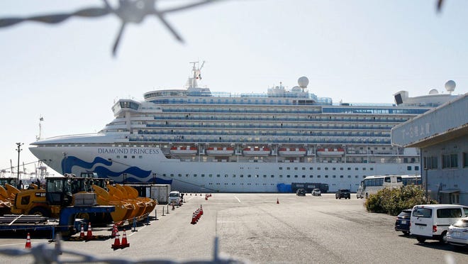 The quarantined ship Diamond Princess is pictured through barbed wire at Yokohama port in Yokohama, near Tokyo Monday, Feb. 17, 2020. Japanese officials have confirmed 99 more people infected by the new virus aboard the ship, the Health Ministry said Monday. (Mayuko Isobe/Kyodo News via AP)