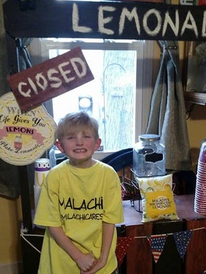 Malachi Fronczak smiles in front of his lemonade stand. Selling lemonade and hot coco, he raised nearly $7,000 this weekend for the family of Deputy Pickett.
