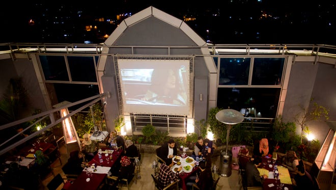 In this Thursday, April 16, 2015 photo, Palestinians spend the evening at the rooftop restaurant "Level Up," in Gaza City. When nightfall descends upon Gaza, the glittering lights of the Level Up restaurant seem to be the only bright spot in this darkened city. The owner has vowed to keep the popular nightspot open no matter what; despite being shelled three diferent times during last summer's war with Israel, he rebuilt and re-opened within three weeks of the war's end. (AP Photo/Khalil Hamra)