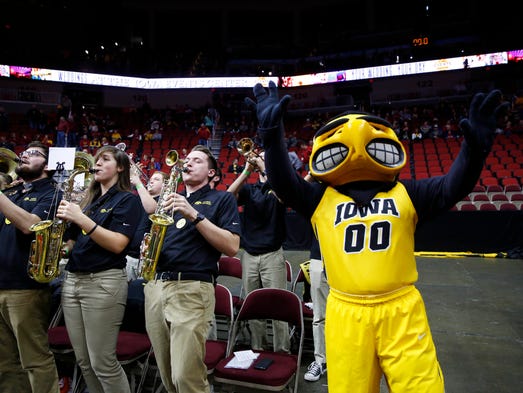 Iowa pep band members play along side the Hawkeye mascot