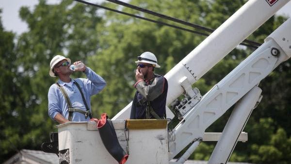 Two Delmarva Power workers take a quick break to hydrate while working in high temperatures.
