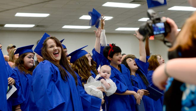 Gennifer Buckner, left, laughs as some of her fellow Community High School graduates throw their caps into the air after receiving their diplomas in a graduation ceremony at A-B Tech's Ferguson Auditorium on Thursday, June 2, 2016. 