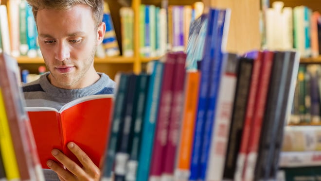 Male student reading book in the library