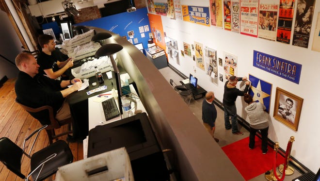 Robert Foster, second from far right, and volunteers Dennis English, second from far right, and Maria Lara, right, work on putting up a poster with a star for singer Frank Sinatra at the Hoboken Historical Museum in Hoboken, N.J. on Nov. 24, 2015. The museum is hosting an exhibit celebrating Sinatra's upcoming 100th birthday on Dec. 12. At left, volunteers Steve Brylski, left, and Jim Corio work correspondence which will be sent out to museum members.