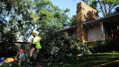 Dan Nielson, with the City of Sioux Falls, works to clean up a downed tree after strong winds early Sunday morning blew it down onto a house at the corner of 26th Street and Duluth Avenue on Sunday, Aug. 24, 2014, in Sioux Falls, S.D. "It just sounded like a jet taking off all night," said Rob Loe, who lives next door.