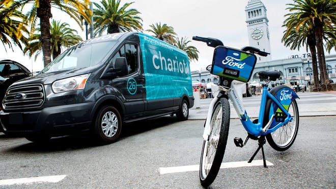 This Thursday, Sept. 8, 2016, photo taken in San Francisco and provided by Ford Motor Company shows a Ford Transit passenger van operated by Chariot shuttle service and a bicycle operated by bike-share company Motivate. Ford Motor Co. announced Sept. 9, 2016, it is buying the app-based shuttle service Chariot and is partnering with bike-share company Motivate as part of its ongoing effort to expand its traditional business.